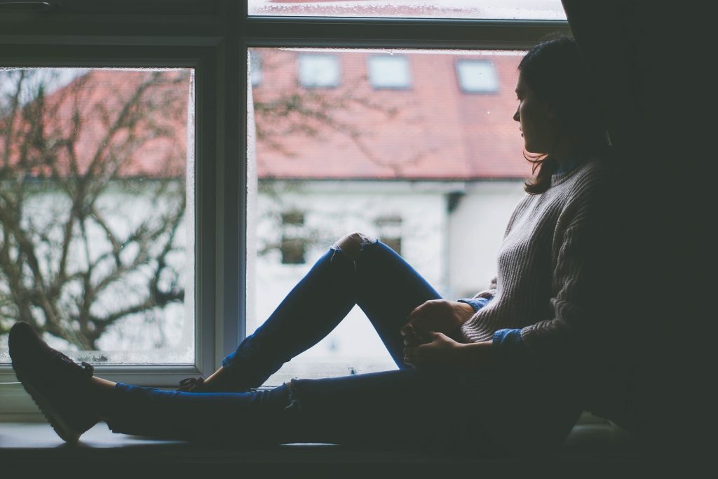 kobieta siedząca na oknie - depresja i jej objawy
