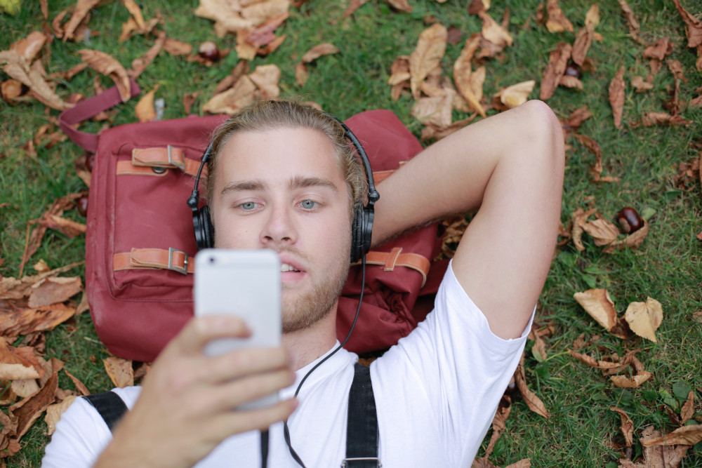 chłopak leży na trawie i słucha muzyki