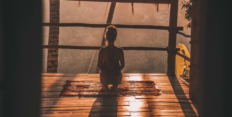 młoda kobieta medytująca o wschodzie słońca