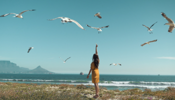 kobieta nad morzem tańcząca pośród białych ptaków