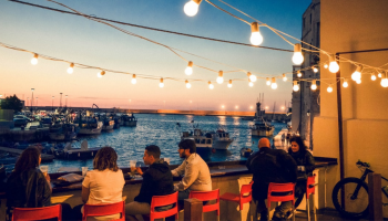 ludzie siedzący przy stolikach w nadmorksiej restauracji, wieczór, klimatyczne światła