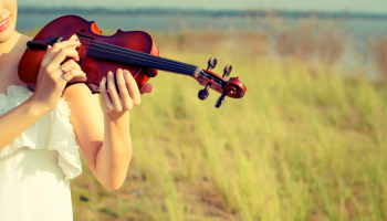kobieta grająca na skrzypcach na łące