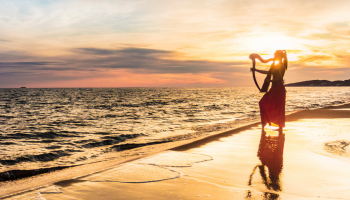kobieta idąca po plaży podczas zachodu słońca