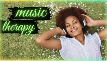 uśmiechnięta kobieta z słuchawkami na uszach leżąca na trawie