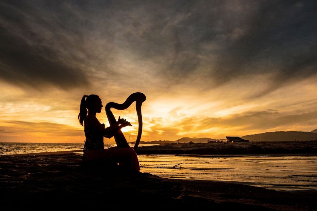 kobieta gra na harfie przy zachodzie słońca