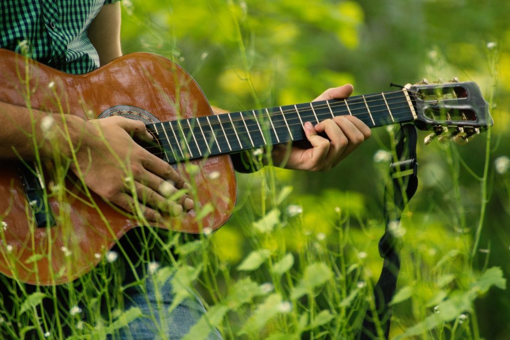 mężczyzna gra w trawie na gitarze