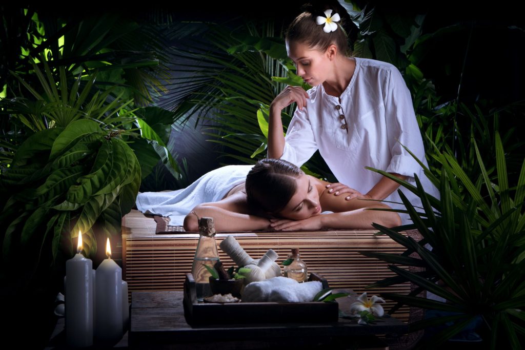 masaż w spa, kobieta masuje klientkę, wokół mnóstwo zielonej roślinności