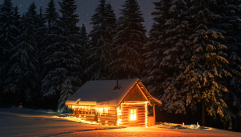 ciemna noc w lesie, świecąca się drewniana chatka, zima