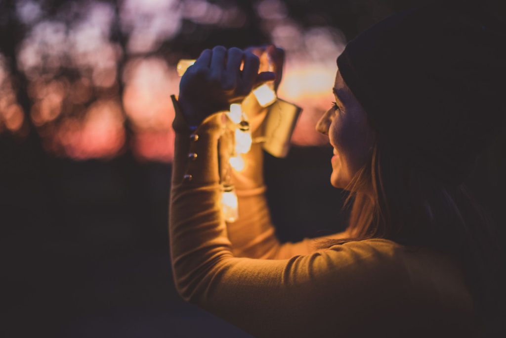 dziewczyna trzyma lampki w dłoniach i jest na zewnątrz w nocy